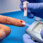 What Is Diabetes? Symptoms, Causes & Prevention Guide Person checking blood sugar using a glucometer at home to manage diabetes and prevent complications