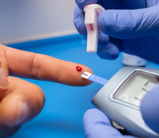 Person checking blood sugar using a glucometer at home to manage diabetes and prevent complications