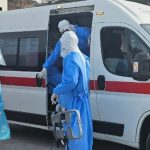 Medical team wearing PPE transferring a patient into an ambulance during emergency infectious disease response