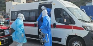 Medical team wearing PPE transferring a patient into an ambulance during emergency infectious disease response