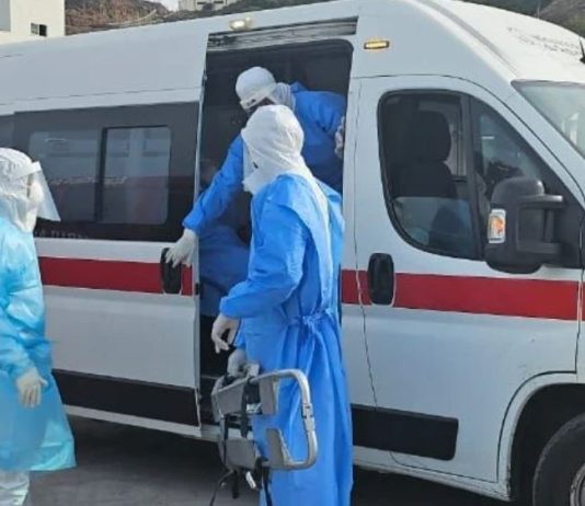 Medical team wearing PPE transferring a patient into an ambulance during emergency infectious disease response
